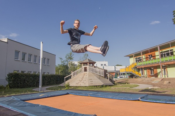 pädagogische Fachkraft des Kindergarten Sportforum in Jena eine pädagogische Fachkraft der Kita Sportforum springt auf dem Boden-Trampolin im Garten der Kita