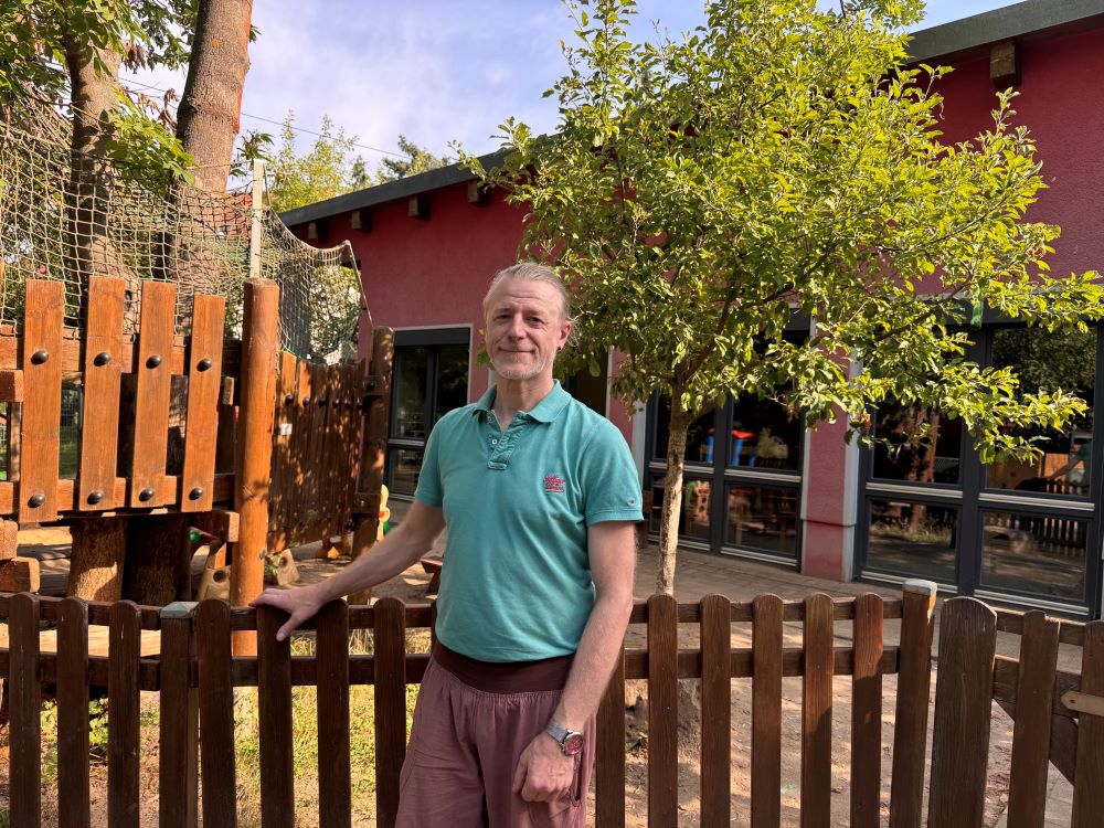 Im Interview mit Abschluss Praktikant André Polz-Tänzer aus dem Kindergarten Isserstedt Interviewpartner André Plz-Tänzer steht vor dem Spielplatz der Einrichtung Kindergarten Isserstedt und lächelt in die Kamera